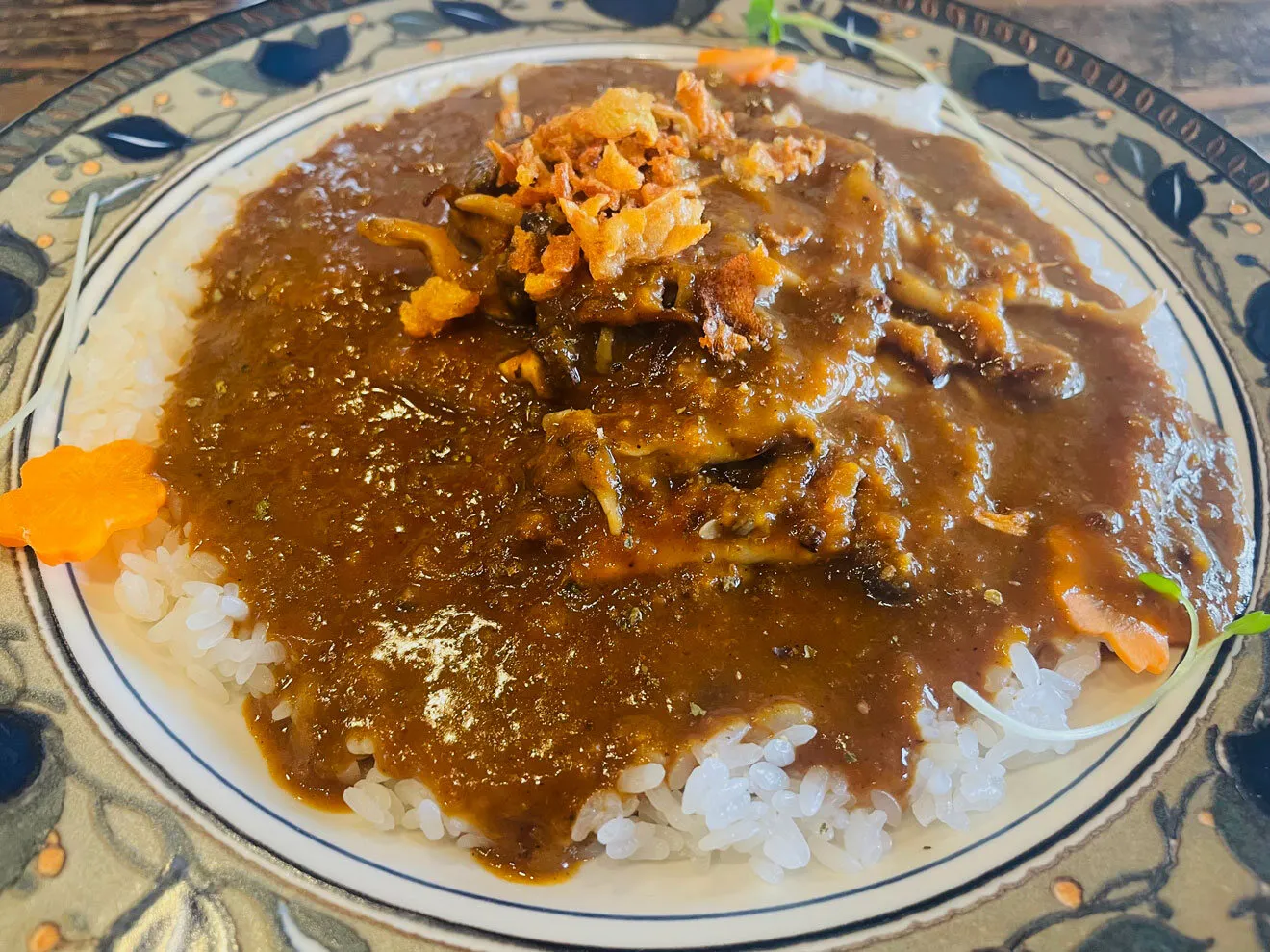 青い草花の絵付けの皿に盛られた、茄子とトマトの欧風カレー